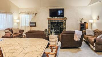 A living room with a fireplace, sofas, a TV, and a dining table.