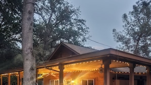 A wooden cabin with a porch, string lights, and a small garden area.