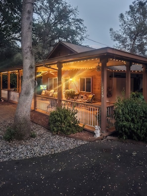 A wooden cabin with a porch, string lights, and a small garden area.