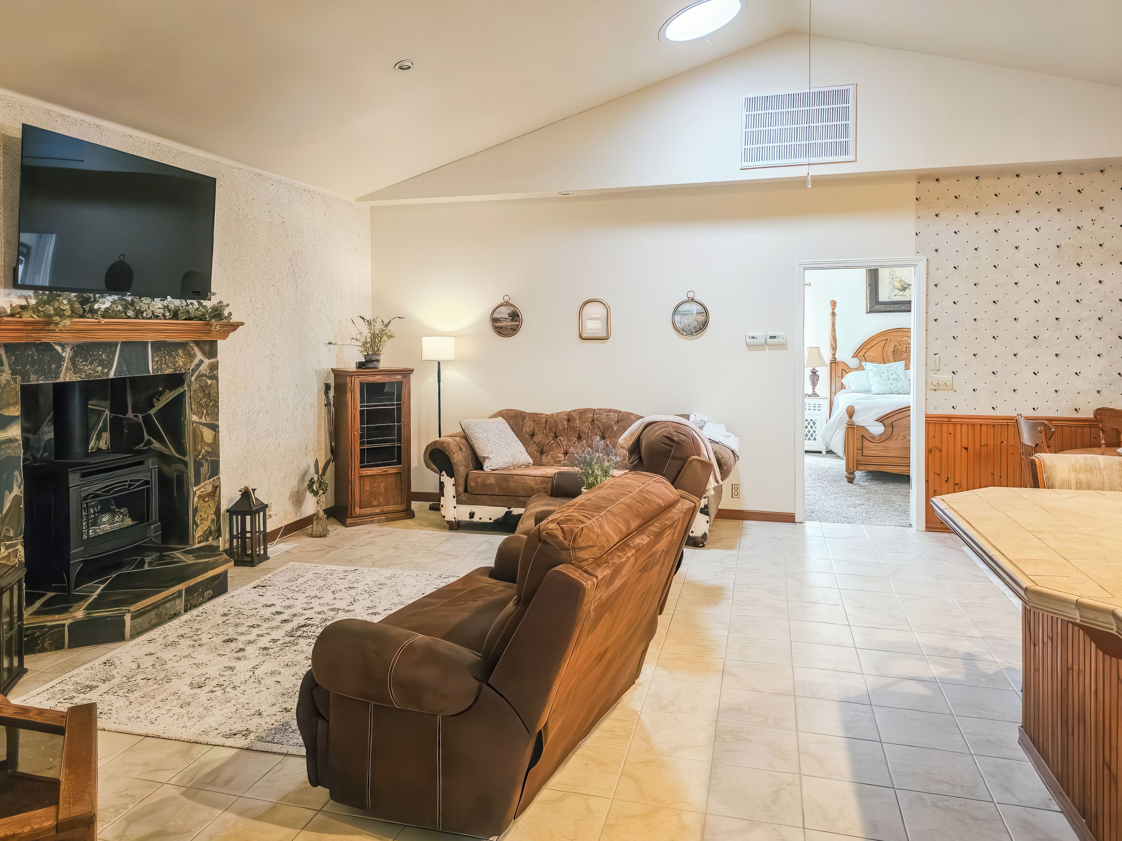 A spacious living room with a fireplace, a sofa, a dining area, and a view into another room.