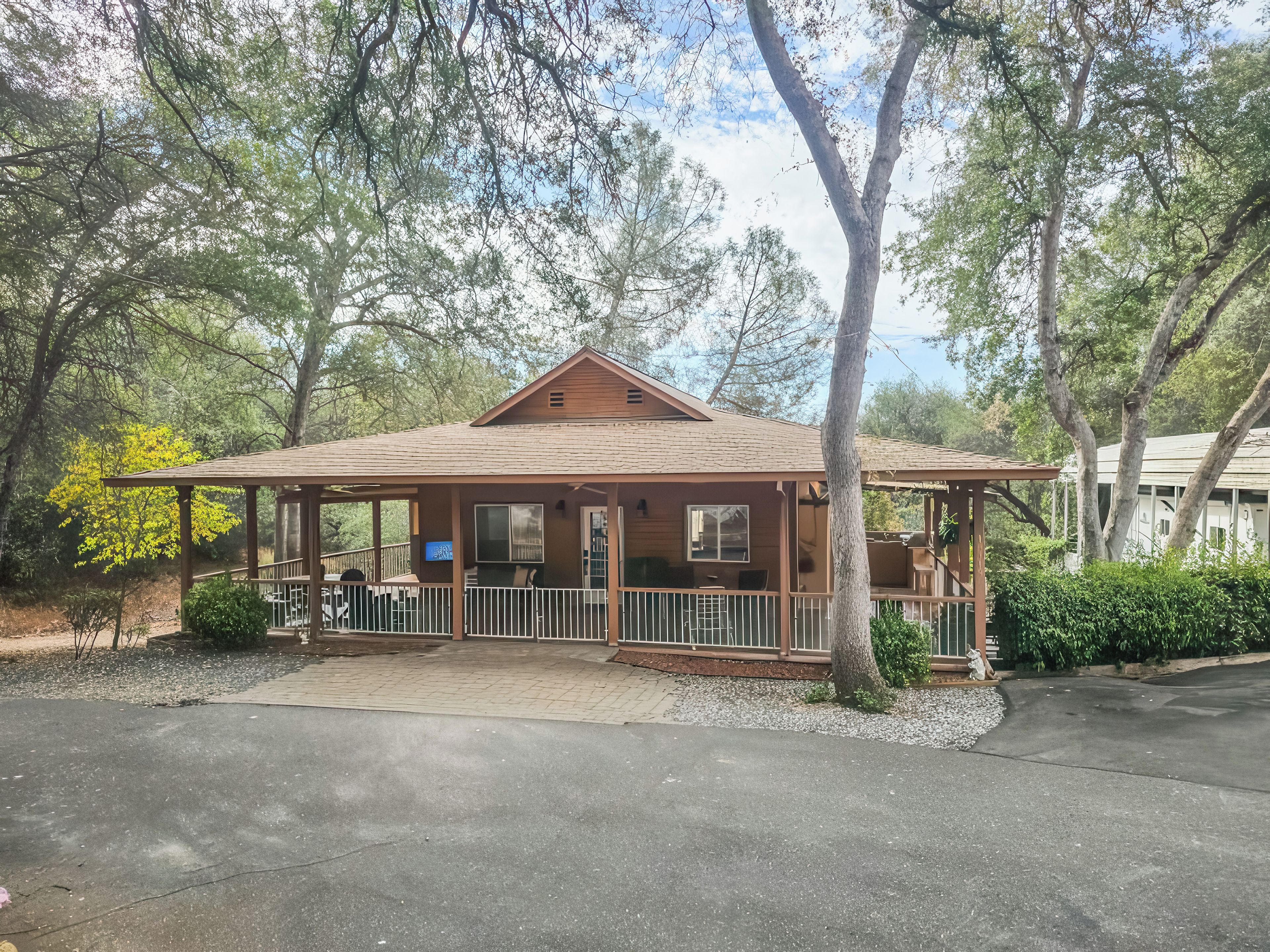 A wooden cabin with a porch, a TV mounted on the wall, and a fenced outdoor seating area.