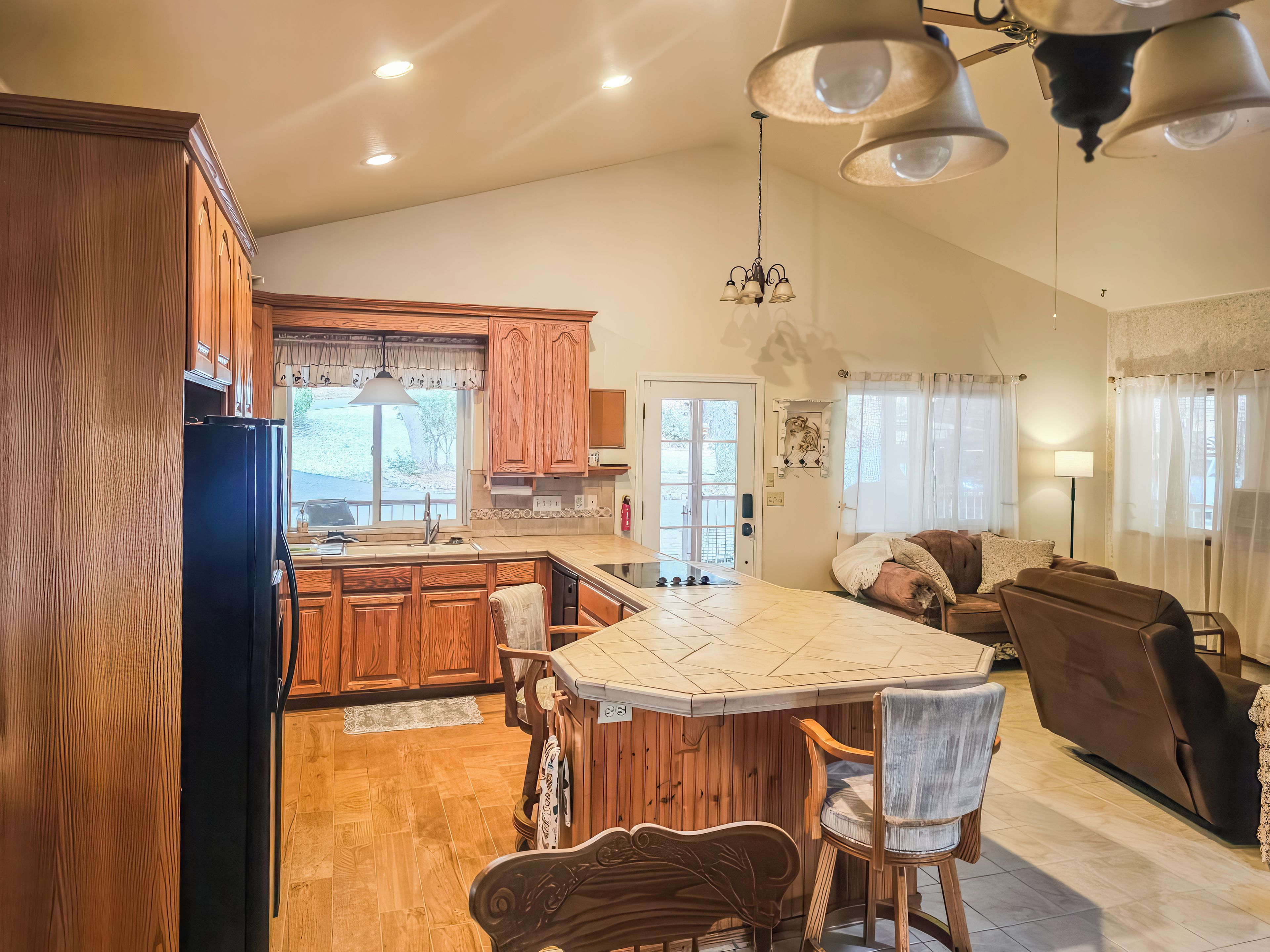 A spacious kitchen with wooden cabinets, a central island, and a dining area with a sofa and chairs.