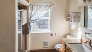 A bathroom with a toilet, sink, and window with curtains.
