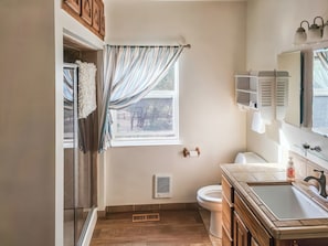 A bathroom with a toilet, sink, and window with curtains.