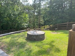 A circular stone structure in a grassy area with a wooden fence in the background.