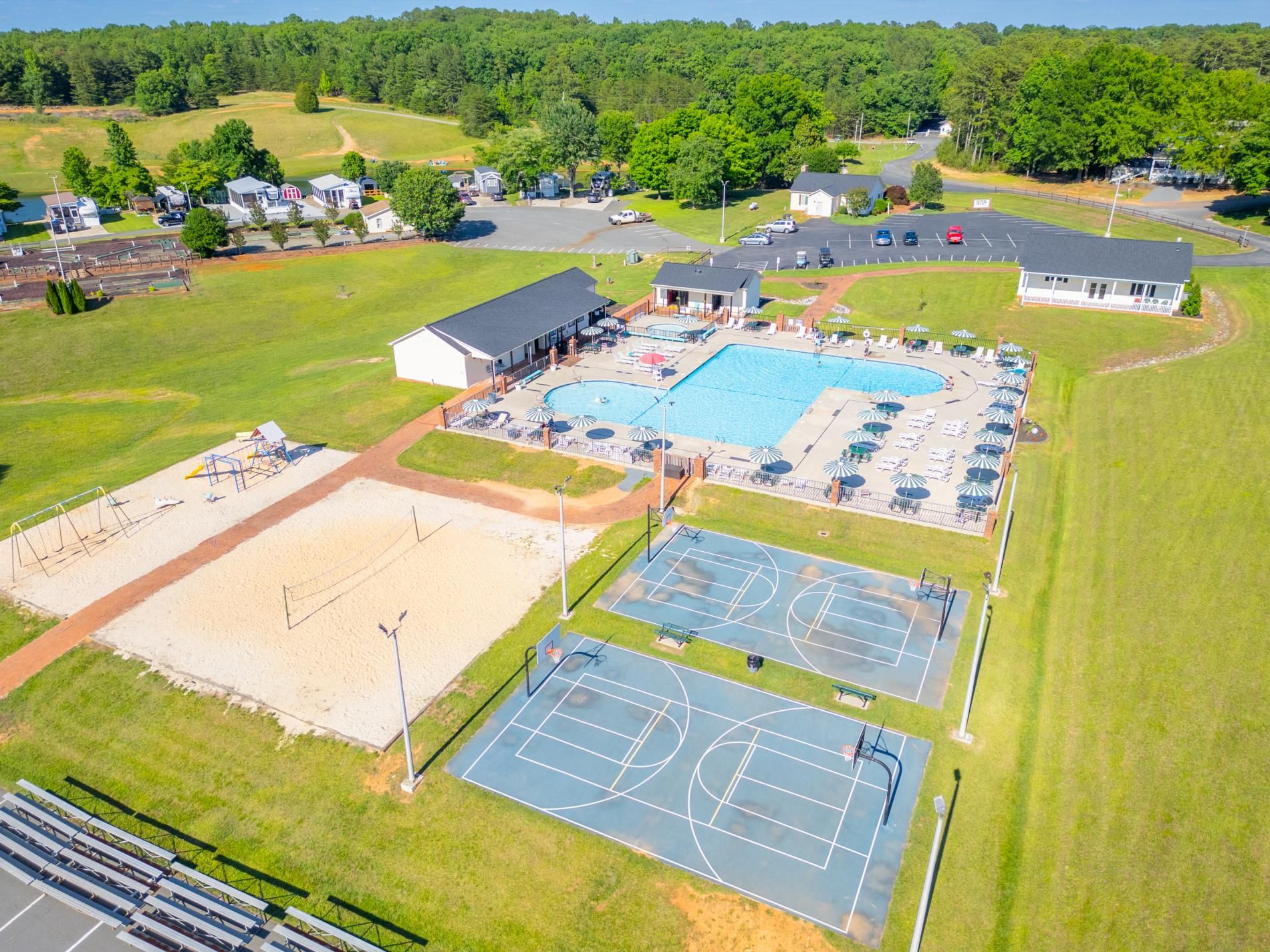 A large outdoor swimming pool with adjacent tennis courts and a covered seating area.