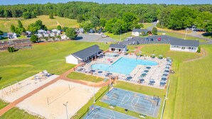 A large outdoor swimming pool with adjacent tennis courts and a covered seating area. - Hickory Heaven by the Lake (New London)