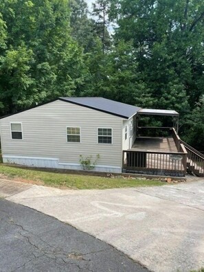 A single-story mobile home with a front porch and a small deck.