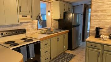 Una cocina con gabinetes verde claro, un refrigerador de acero inoxidable y salpicadero de azulejos.