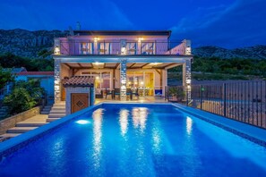 Ein zweistöckiges Haus mit Swimmingpool, Außenbereich und Bergblick.