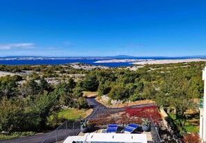 A coastal landscape with a road leading to a building with solar panels and a view of the sea. - Cozy 2-bedroom house in a serene spot with AC (Jablanac)