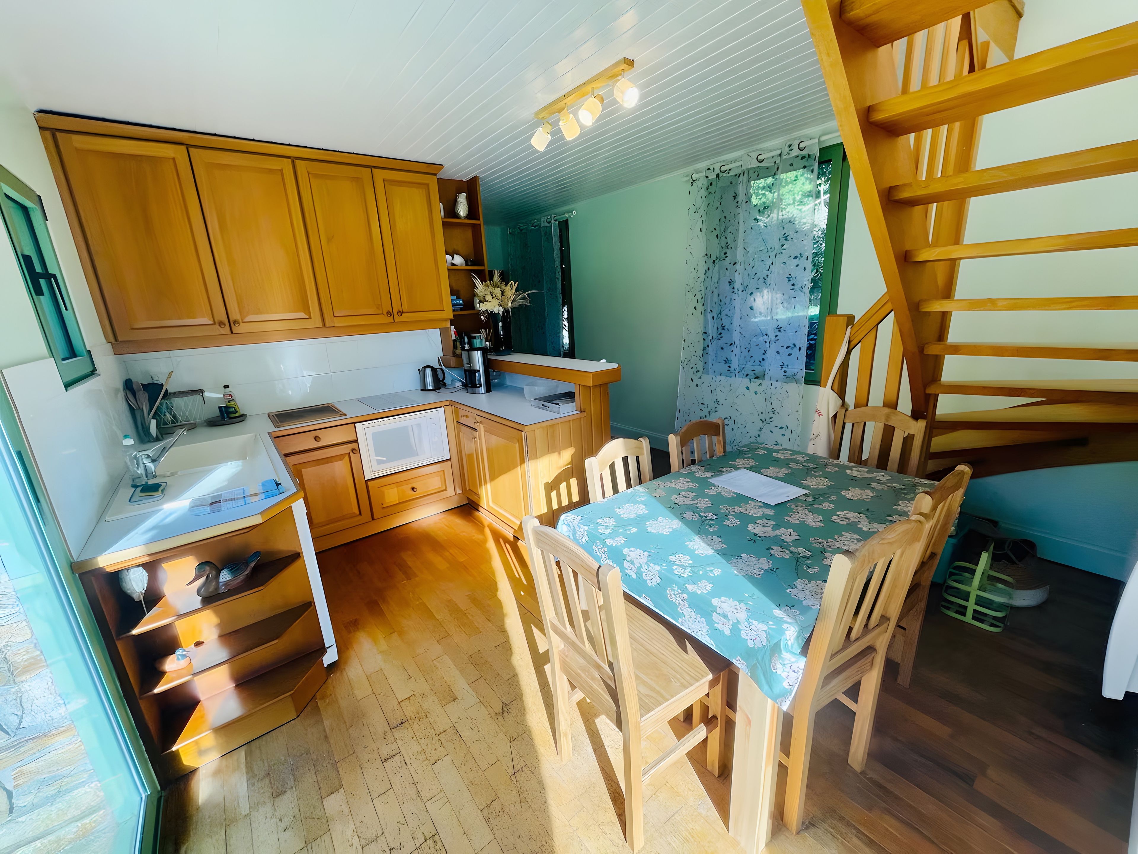 Une cuisine avec des meubles de rangement en bois, un évier et un coin repas comprenant une table et des chaises.