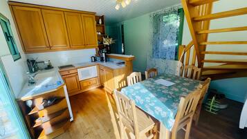 Une cuisine avec des meubles de rangement en bois, un évier et un coin repas comprenant une table et des chaises.