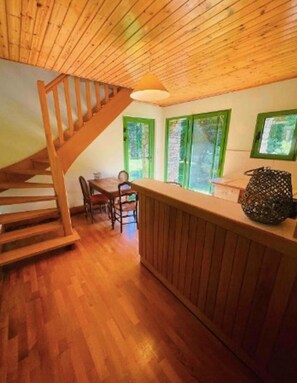 A wooden interior with a staircase, a dining area, and a window with a view.