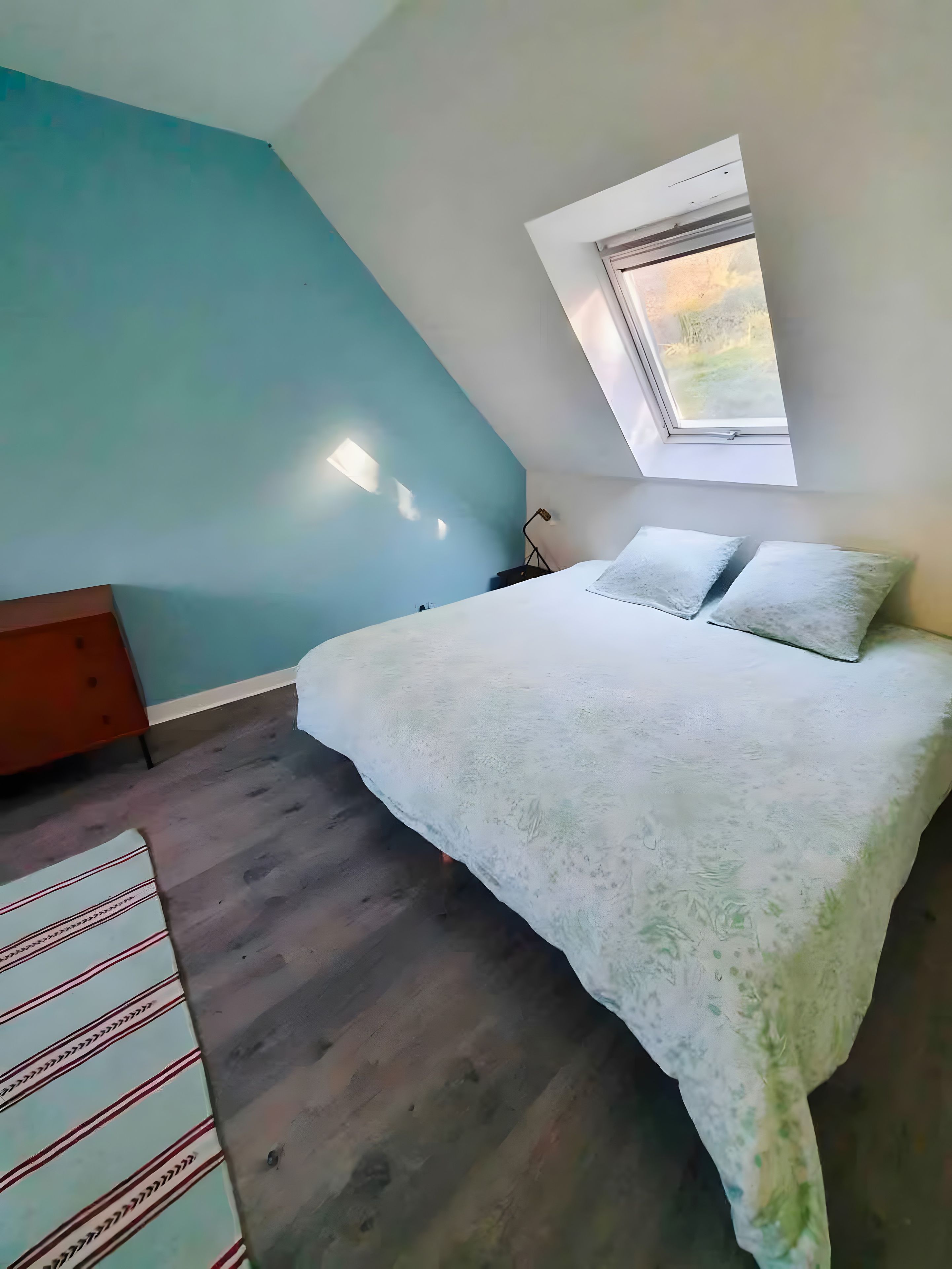 Een slaapkamer met een bed, een raam en een nachtkastje.