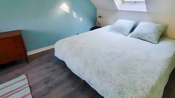 Een slaapkamer met een bed, een raam en een nachtkastje.