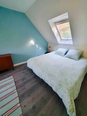 A bedroom with a bed, a window, and a nightstand.