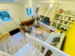 Un salon chaleureux avec une cheminée, des étagères à livres et un escalier.