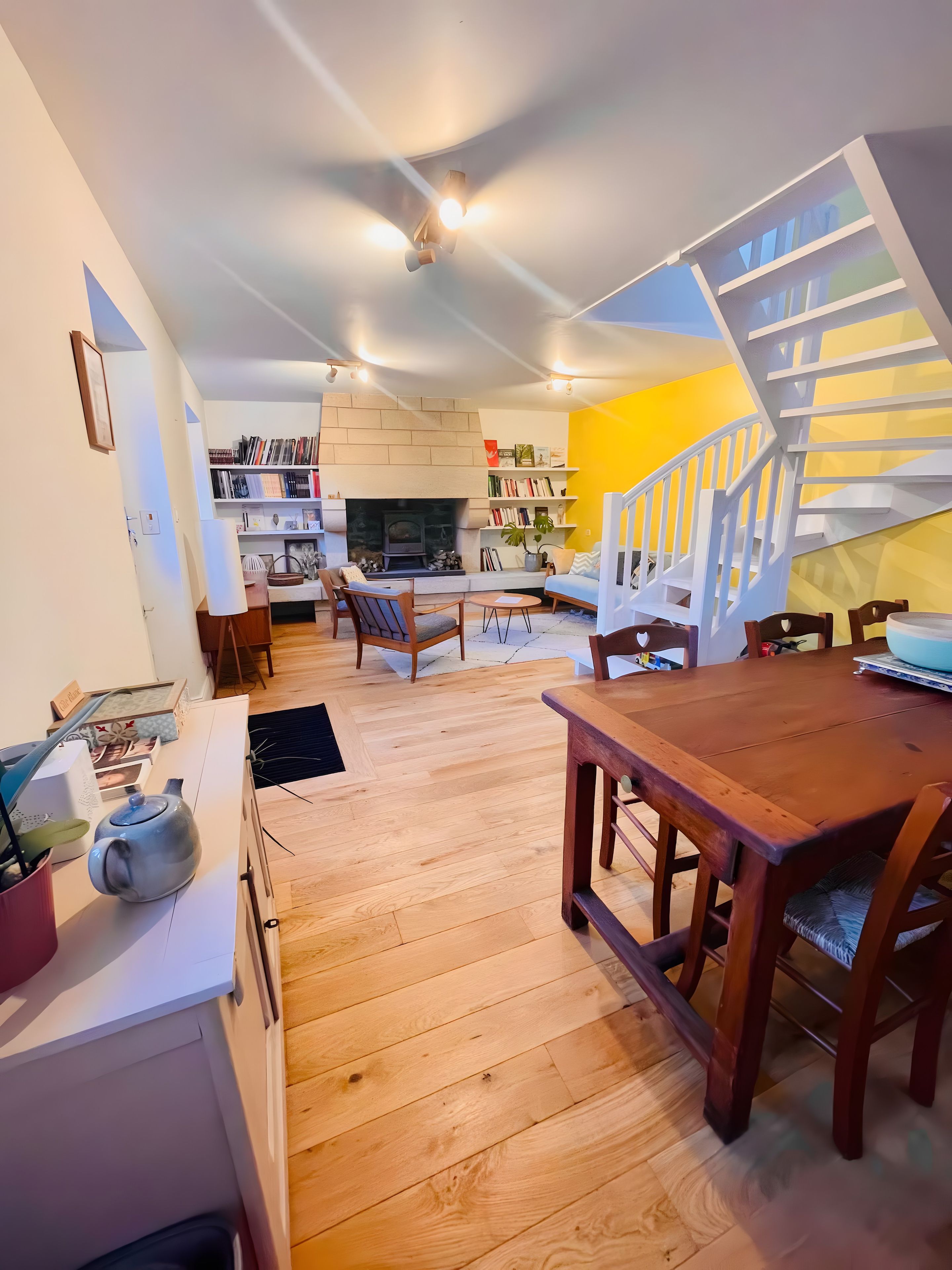 Un salon moderne avec une cheminée, un plancher en bois, une table à manger et un escalier.