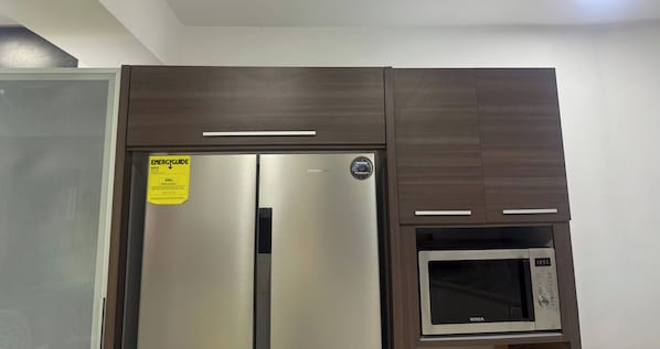 A kitchen with a stainless steel refrigerator and a built-in microwave.