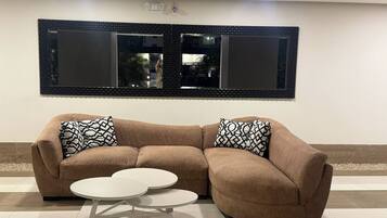 A modern living room with a sectional sofa, two patterned throw pillows, and a small round coffee table.