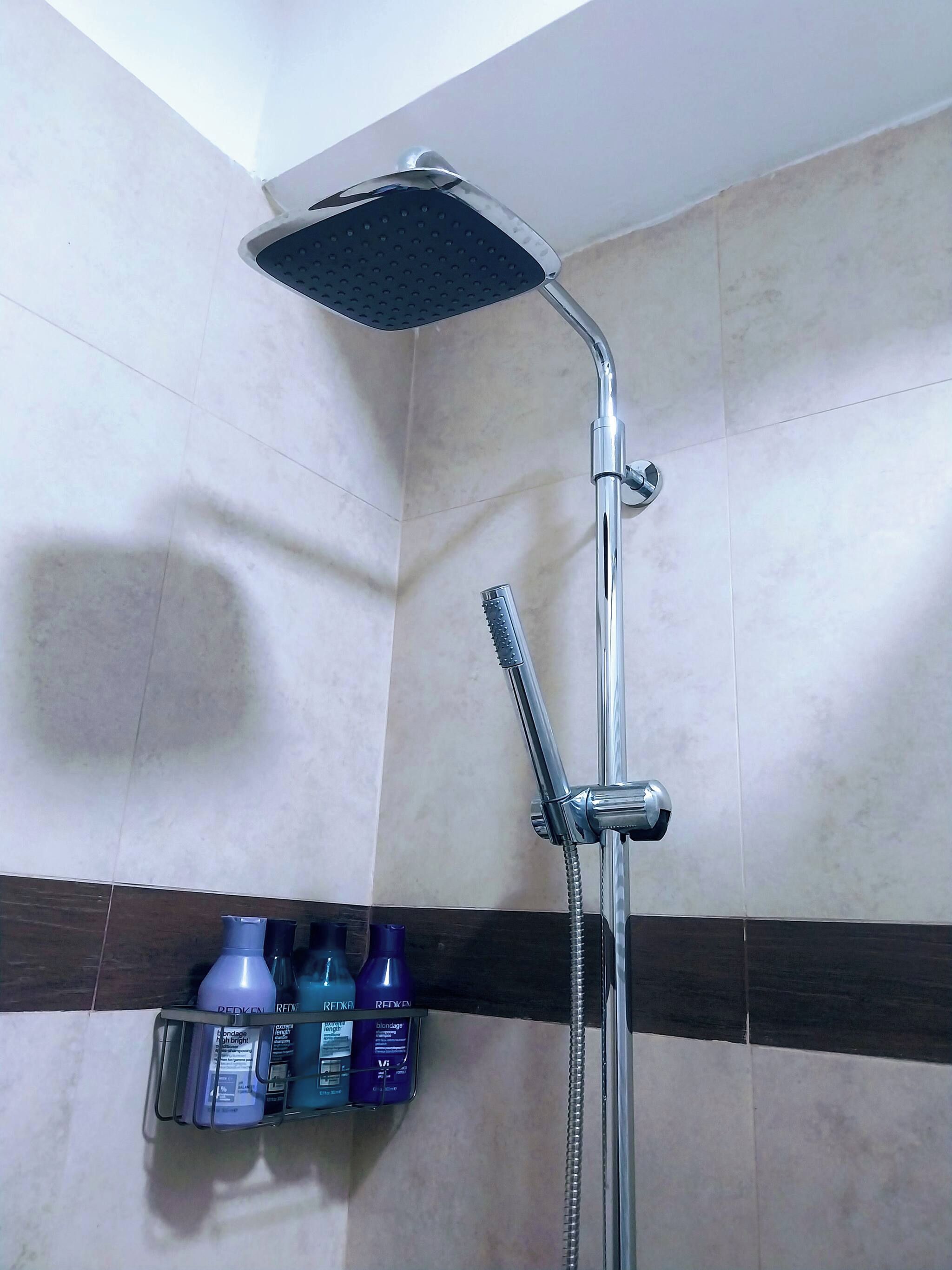 Une douche équipée d’un pommeau de douche à main et d’un robinet de contrôle fixé au mur.