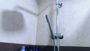 Une douche équipée d’un pommeau de douche à main et d’un robinet de contrôle fixé au mur.