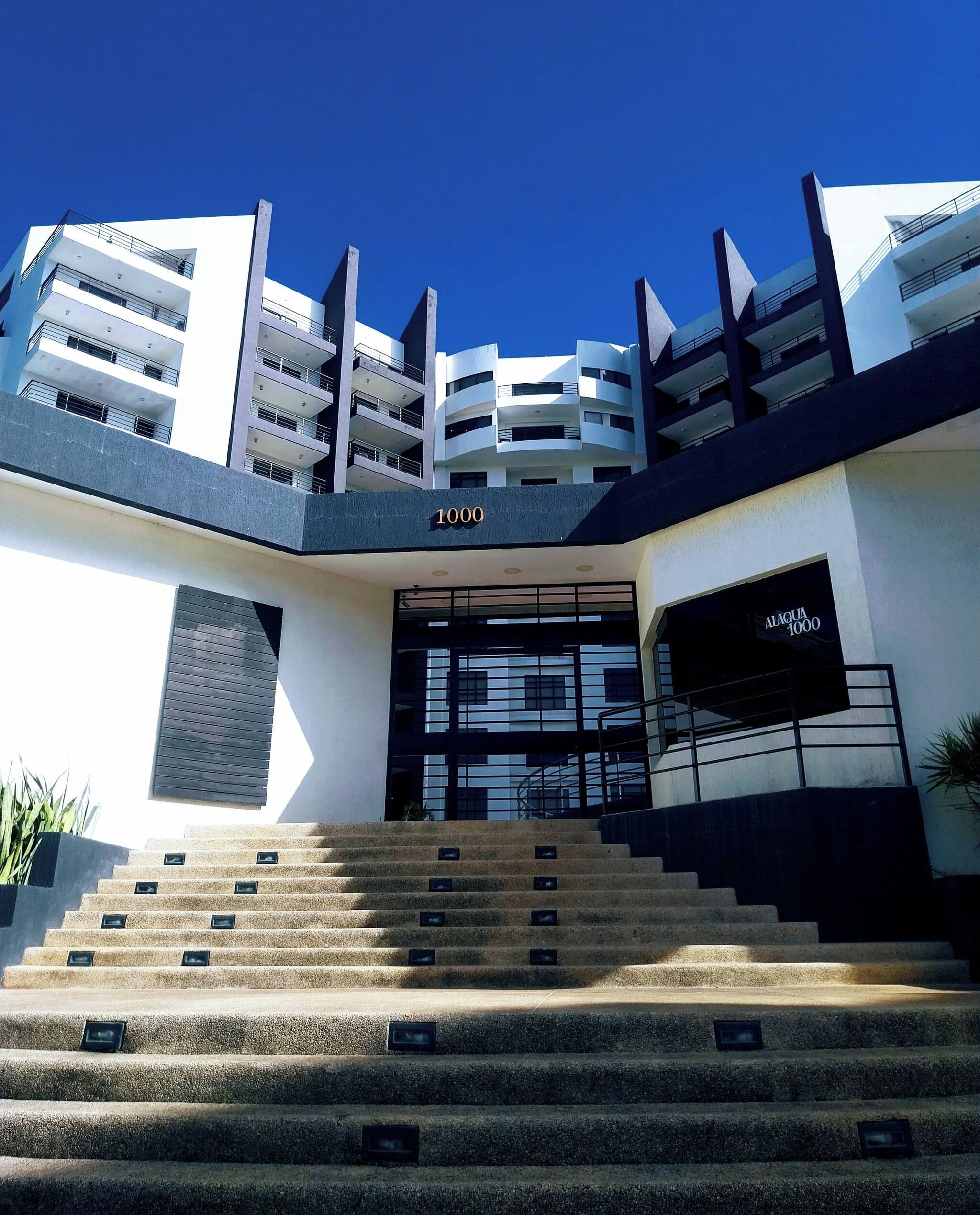 A modern building with a staircase leading to a gated entrance.