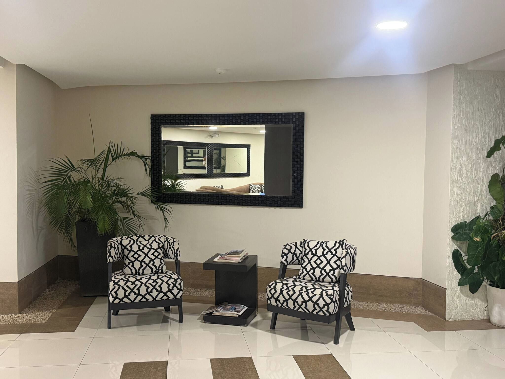 A reception area with two armchairs, a small table, and a large mirror on the wall.