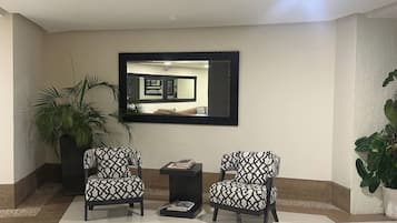 A reception area with two armchairs, a small table, and a large mirror on the wall.