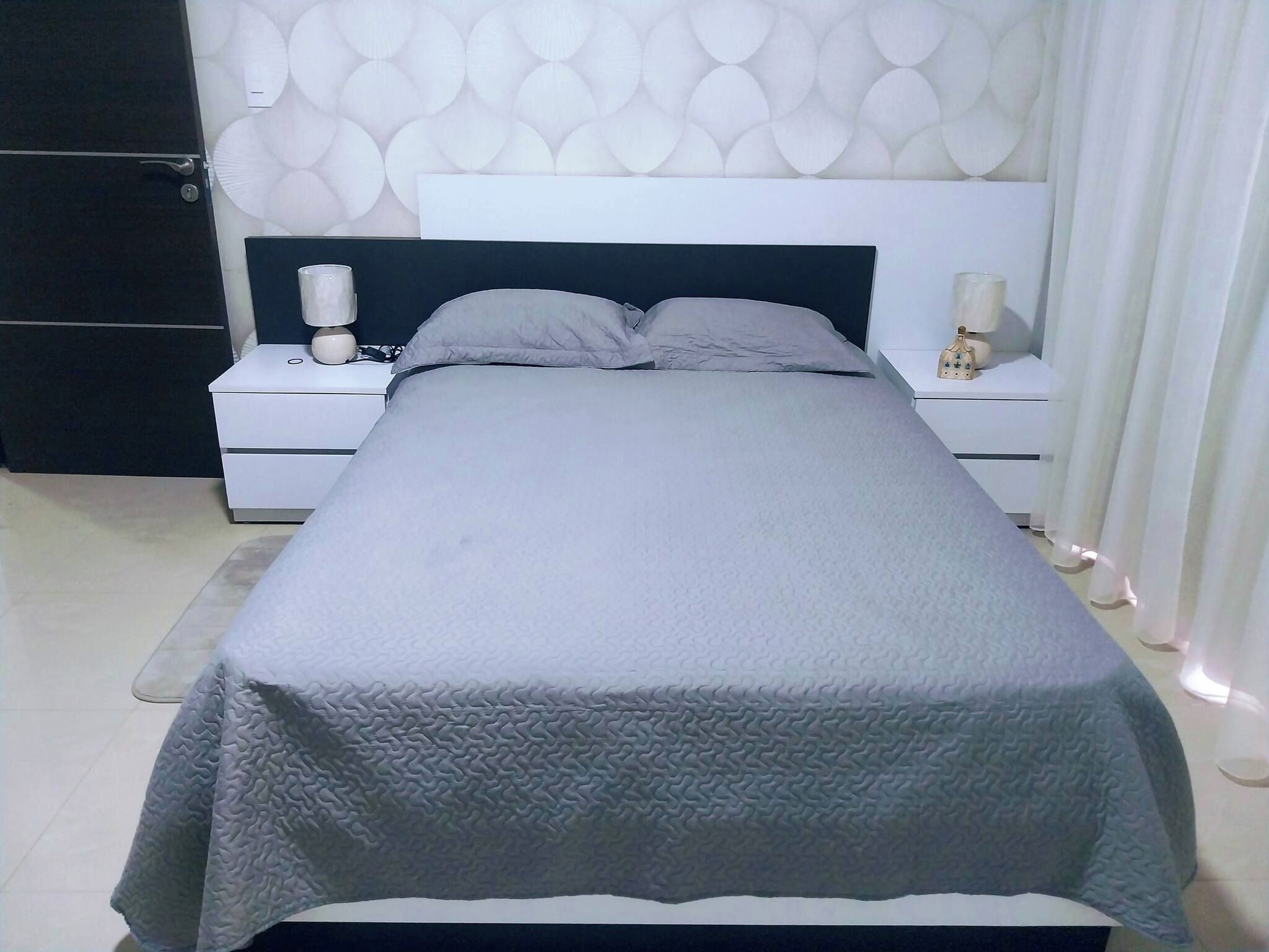 Een moderne slaapkamer met een bed, nachtkastjes en een wand met een cirkelpatroon.