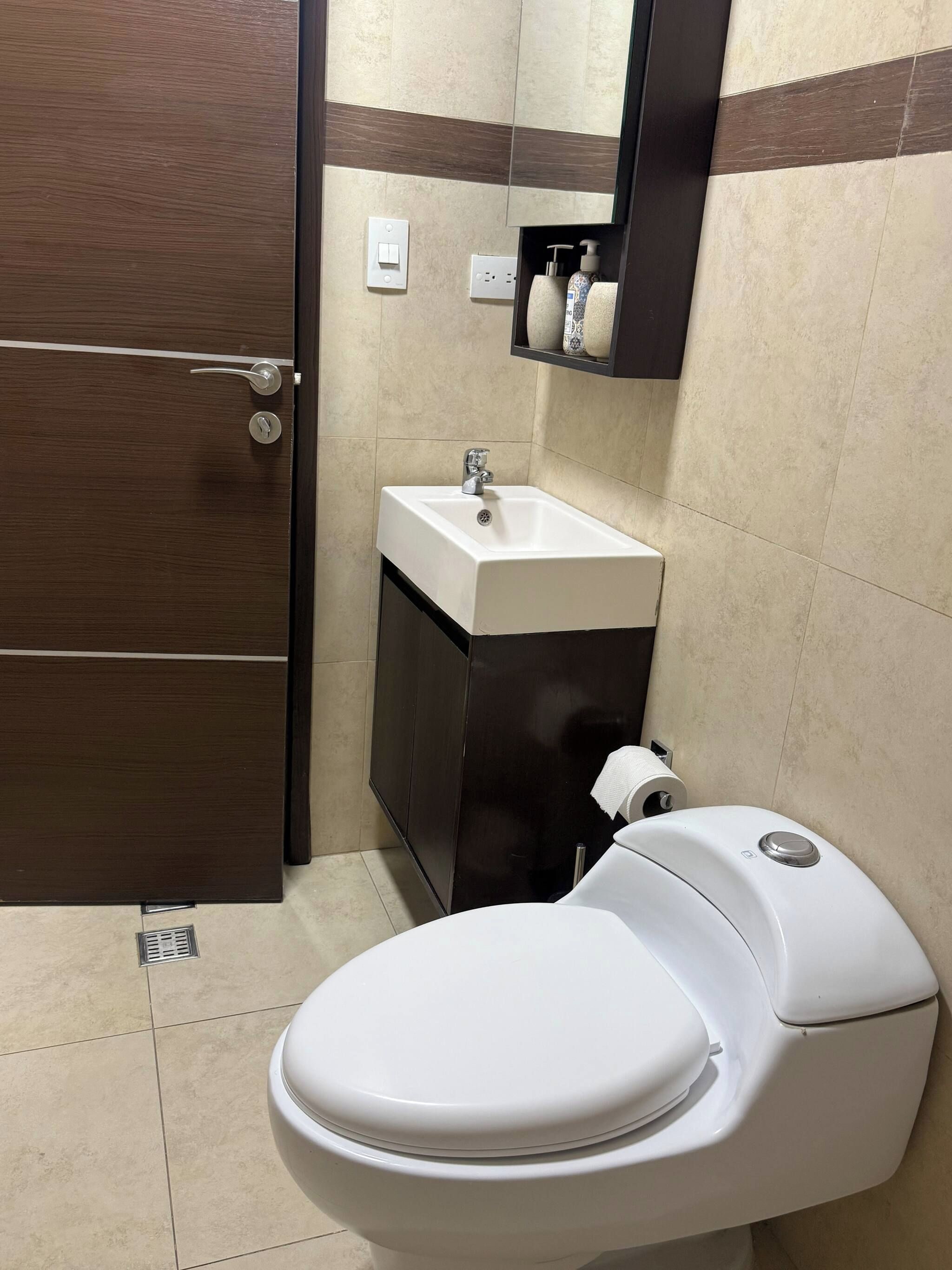 A bathroom with a toilet, sink, and mirror.