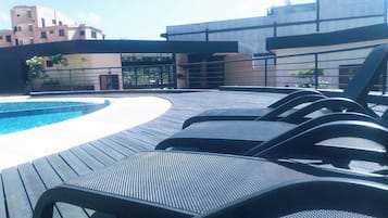 Zona junto a la piscina con sillones de descanso y una piscina.