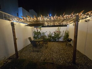 An outdoor patio with a table and chairs, string lights, and a grill. - Casa Tlalocan Acapulco (Acapulto)