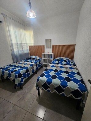 A room with two beds, a wooden headboard, a small shelf, and a hanging light fixture. - Casa Tlalocan Acapulco (Acapulto)