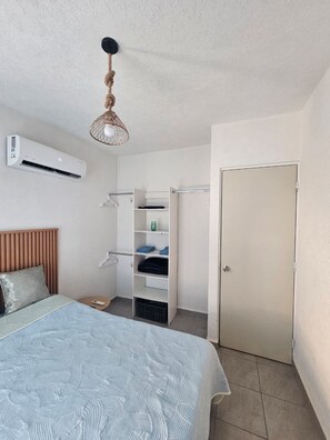 A bedroom with a bed, an air conditioning unit, a wardrobe, and a door. - Casa Tlalocan Acapulco (Acapulto)