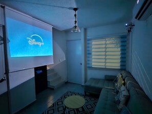 A living room with a flat-screen TV displaying the Disney+ logo, a sofa, a patterned rug, and a ceiling fan. - Casa Tlalocan Acapulco (Acapulto)
