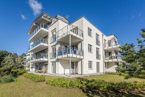 A multi-story residential building with balconies, a flat roof, and a well-maintained garden. - Vacation Rental with Sauna, Recreation Room, and Rural Tranquility (Zirchow)