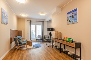 Ein modernes Wohnzimmer mit Holzboden, einem blauen Sofa, einem kleinen runden Tisch, einer Stehlampe und einem Bild an der Wand.