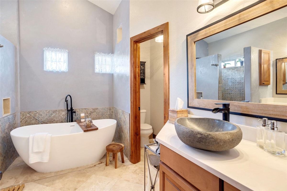 Un baño moderno con una bañera independiente, un espejo grande y un lavabo de piedra.