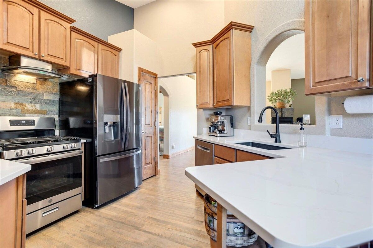 A modern kitchen with stainless steel appliances, wooden cabinets, and a marble countertop.