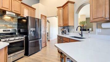 A modern kitchen with stainless steel appliances, wooden cabinets, and a marble countertop.