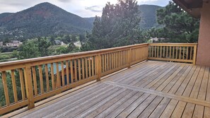 Una terraza de madera con barandilla que da vista a un paisaje montañoso.