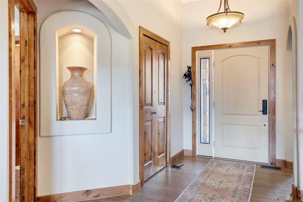 Un pasillo con puertas de madera, un tapete y un jarrón en la pared.
