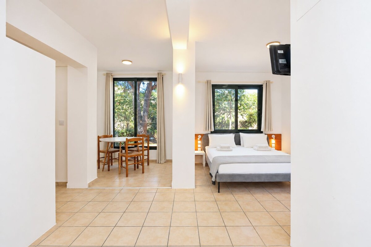 A bedroom with a bed, bedside table, lamp, and a window with curtains.