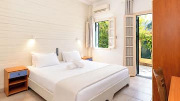 Quarto de hotel com cama, mesas de cabeceira, uma janela e ar condicionado.