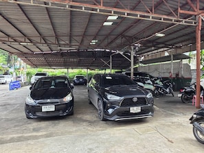 Un área de estacionamiento techada con dos coches y varias motocicletas.