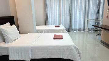 Una habitación de hotel con dos camas, una mesita y una silla.