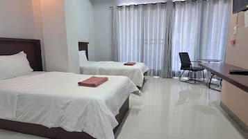A hotel room with two beds, a desk, a chair, and a TV.