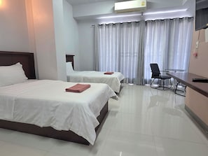 Habitación de hotel con dos camas, un escritorio, una silla y un televisor.
